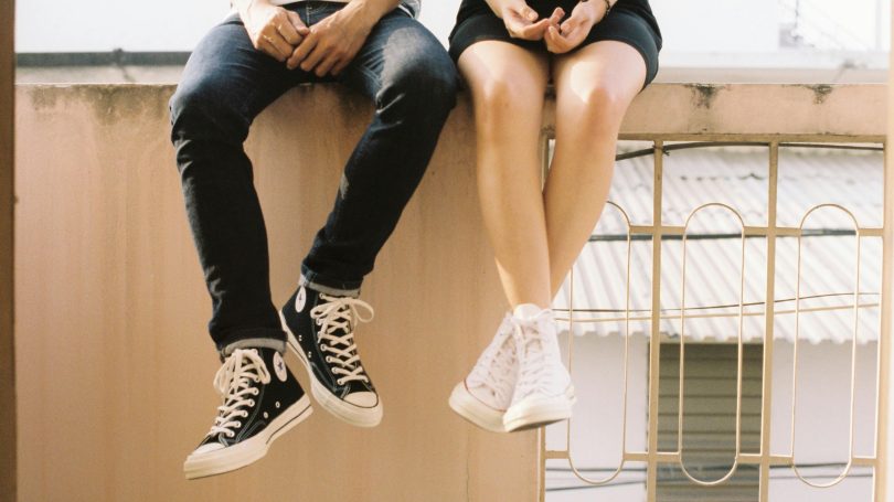 Couple sitting on a ledge wearing casual sneakers