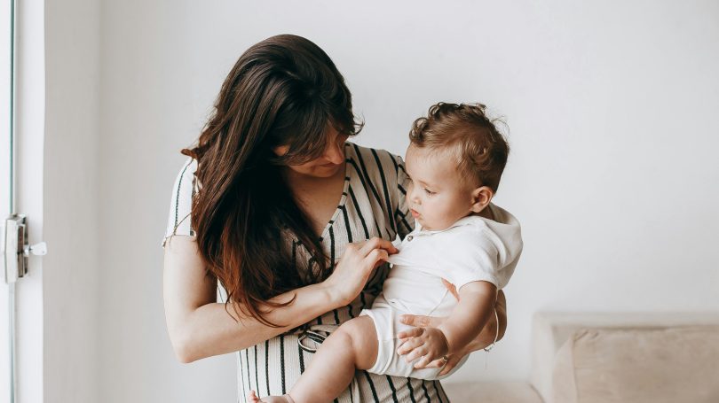 Young mother holding her baby, looking at them with care.
