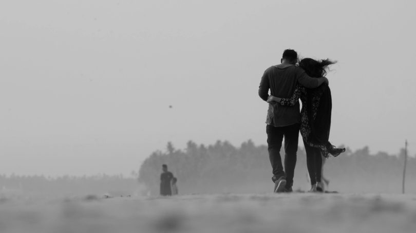Black and white photo of a couple walking on a beach