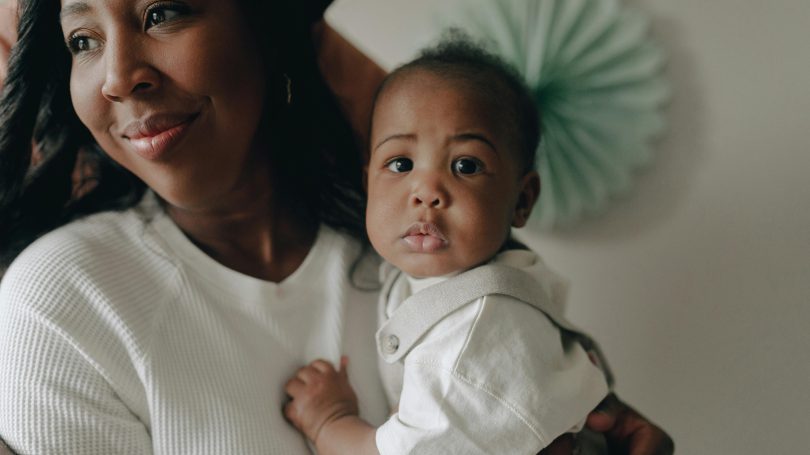 Smiling mother holding her baby, showcasing a strong bond and postpartum well-being.