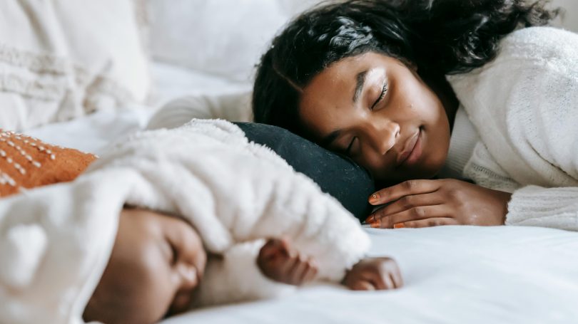 Mother and baby sleeping peacefully on a cozy bed, capturing warmth, love, and tranquility.